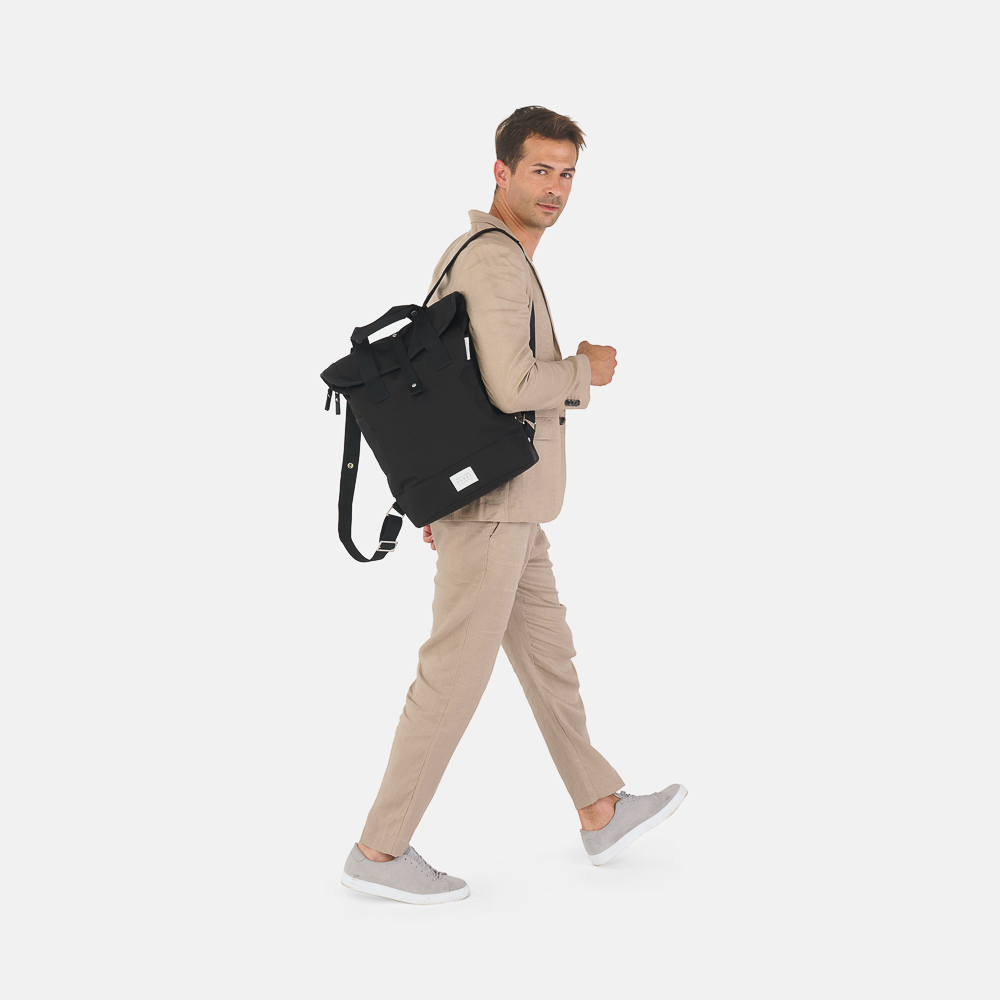 man walking wearing city bikepack black bicycle bag as backpack