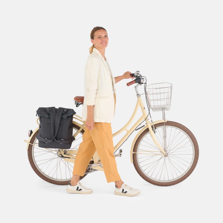woman walking with weathergoods bicycle bag city bikepack xl blue attached to rear pannier rack of bicycle
