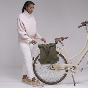 Femme debout avec bicyclette city bikepack olive attaché au porte-vélos